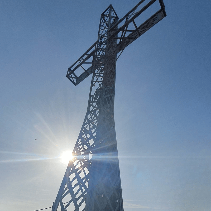 Businessstart mit 40+ – Sinn & Selbstbestimmung auf Deine Art Frau 40+ startet ihr Business – symbolisch dargestellt durch ein Gipfelkreuz von unten gesehen im Sonnenlicht.